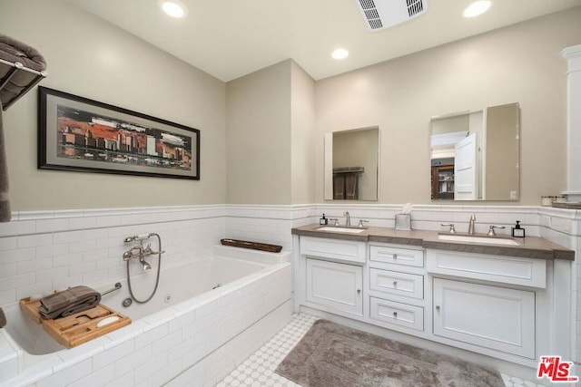 bathroom with vanity and tiled tub