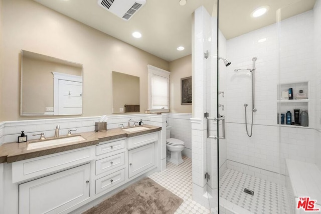 bathroom with walk in shower, vanity, toilet, and tile walls