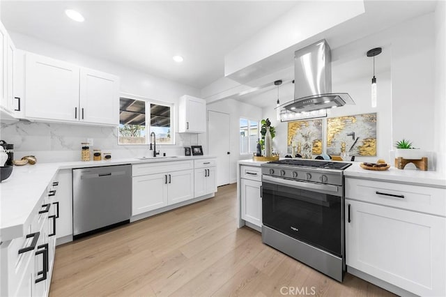 kitchen featuring sink, white cabinetry, hanging light fixtures, stainless steel appliances, and island range hood