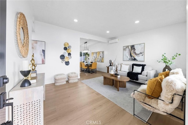 living room featuring a wall mounted air conditioner and light hardwood / wood-style floors