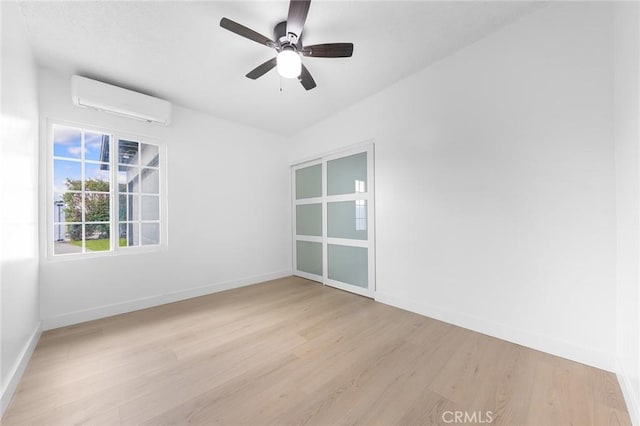 empty room featuring ceiling fan, a wall mounted air conditioner, and light hardwood / wood-style floors