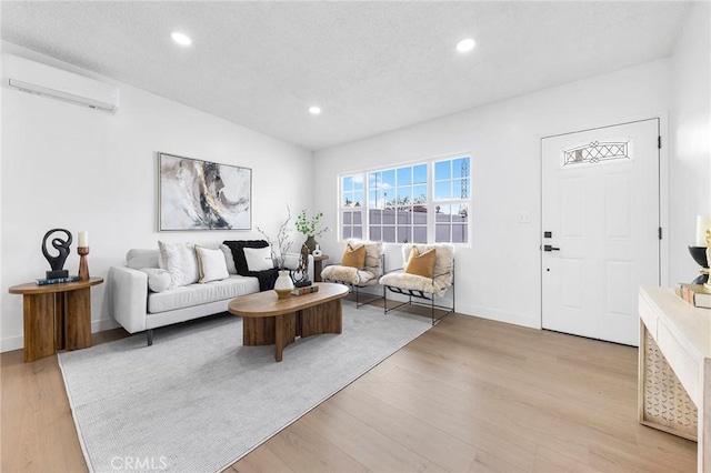 living room featuring a wall mounted air conditioner and light hardwood / wood-style flooring