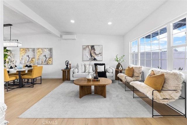 living room featuring a wall unit AC, beamed ceiling, and light wood-type flooring