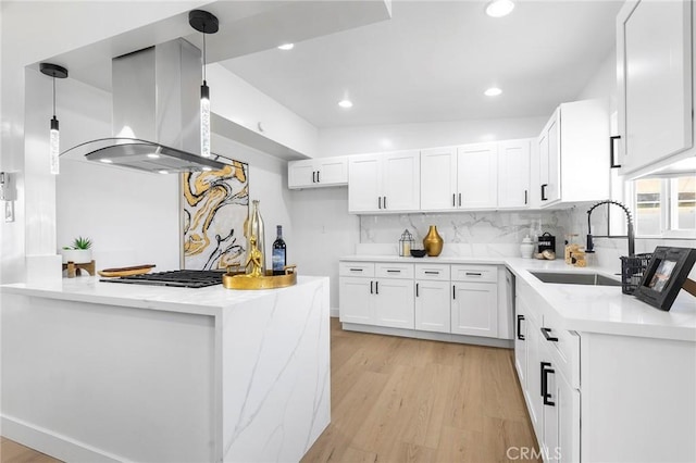 kitchen featuring white cabinetry, hanging light fixtures, island exhaust hood, light hardwood / wood-style floors, and backsplash