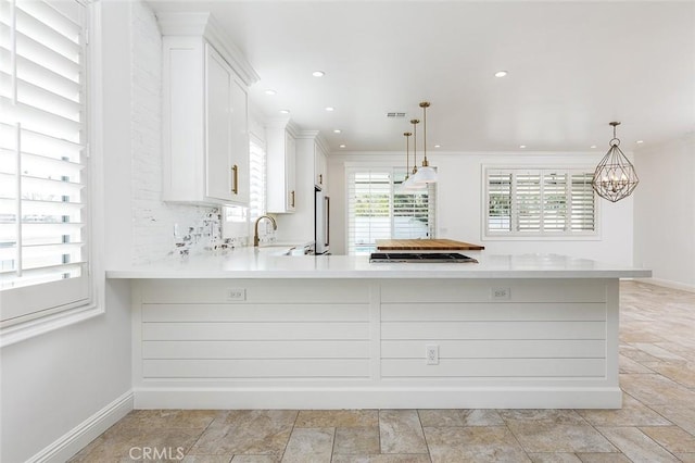 kitchen featuring pendant lighting, white cabinetry, stainless steel appliances, and kitchen peninsula