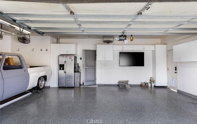 garage with stainless steel fridge with ice dispenser and a garage door opener