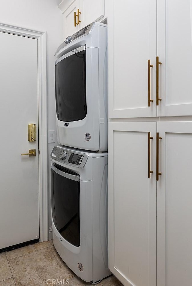 laundry area featuring cabinets, stacked washer / drying machine, and light tile patterned floors