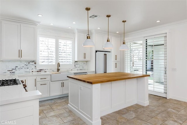 kitchen with a center island, high end fridge, sink, and white cabinets