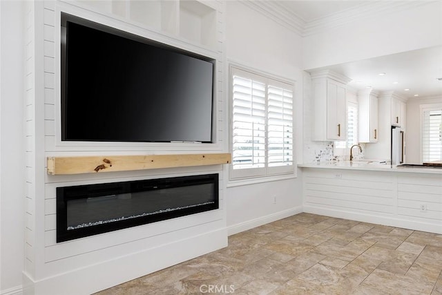 unfurnished living room featuring ornamental molding and sink