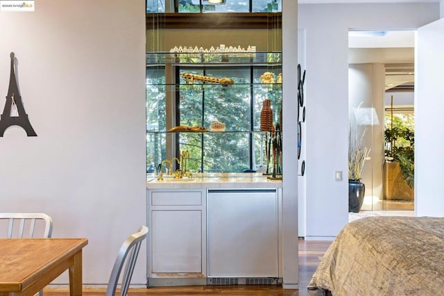 bar featuring hardwood / wood-style flooring, fridge, and sink