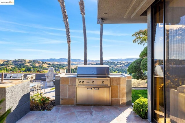 view of patio / terrace with area for grilling, exterior bar, exterior kitchen, and a mountain view