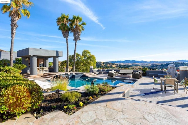 view of pool featuring an in ground hot tub, an outdoor living space, a mountain view, and a patio area