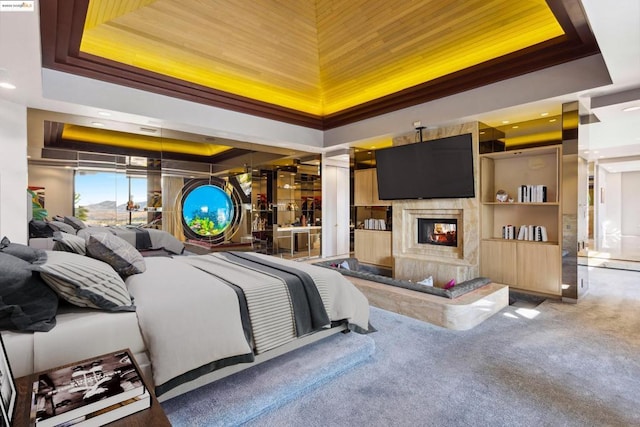 carpeted bedroom with a raised ceiling and a fireplace