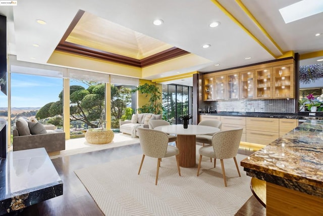 dining space with dark hardwood / wood-style floors, a tray ceiling, and a skylight