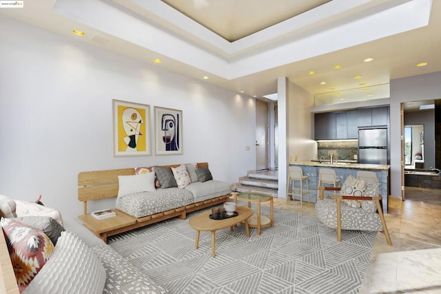 living room featuring a tray ceiling and sink