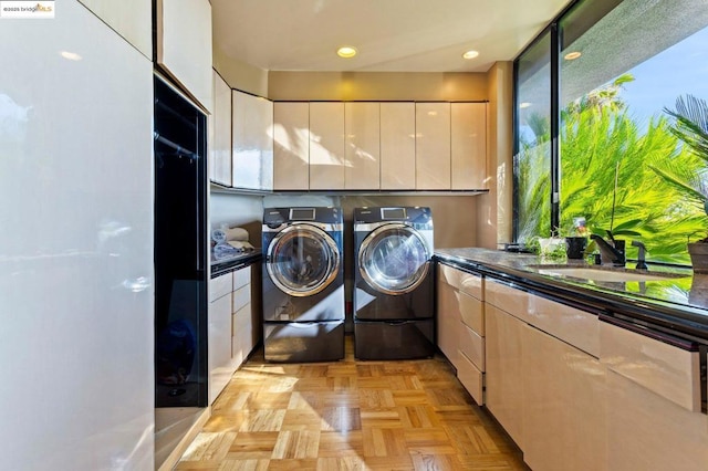 laundry area featuring sink, washing machine and dryer, cabinets, and light parquet floors