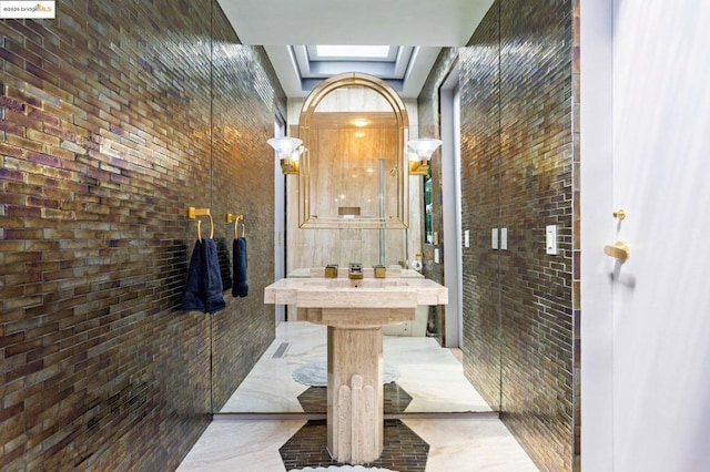 bathroom featuring a skylight and brick wall