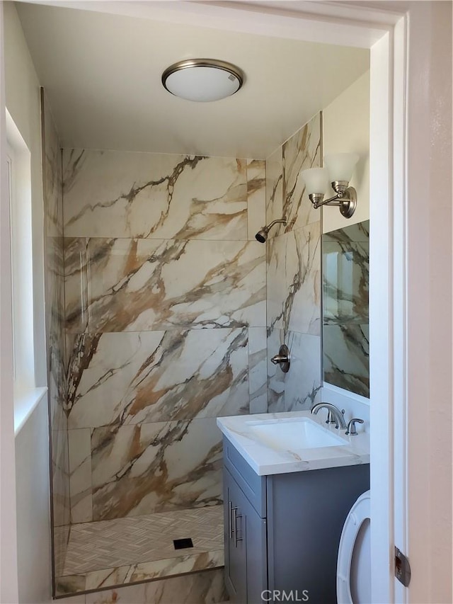 bathroom featuring tiled shower, vanity, toilet, and tile walls