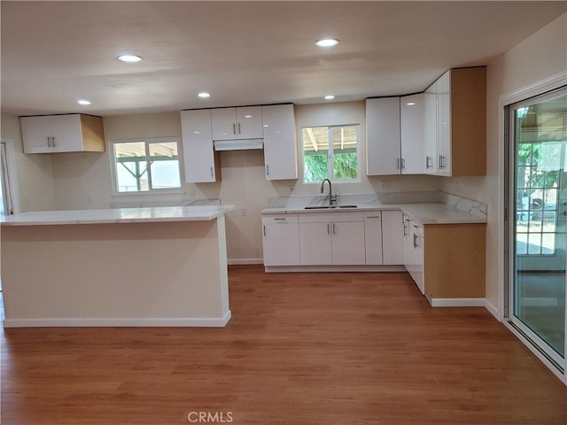 kitchen with sink, light hardwood / wood-style flooring, and white cabinets