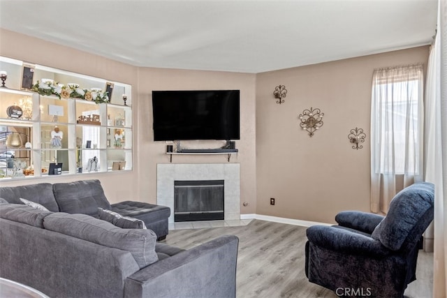 living room featuring a tile fireplace and light hardwood / wood-style flooring