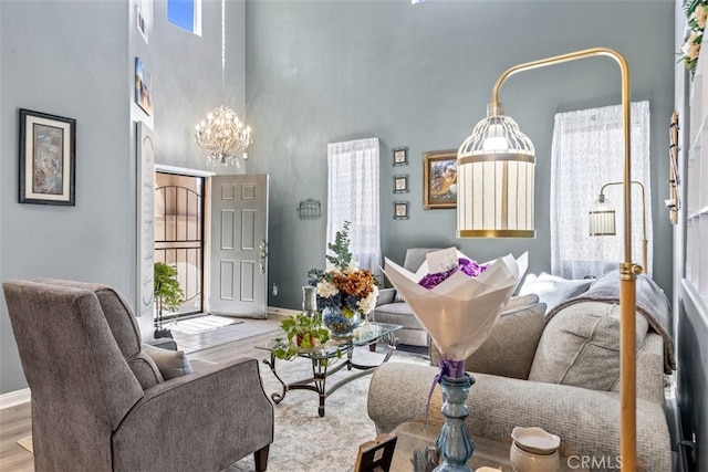 living room with a notable chandelier, light hardwood / wood-style flooring, and a high ceiling