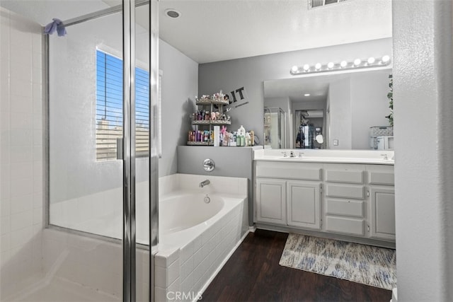 bathroom featuring wood-type flooring, vanity, a textured ceiling, and plus walk in shower