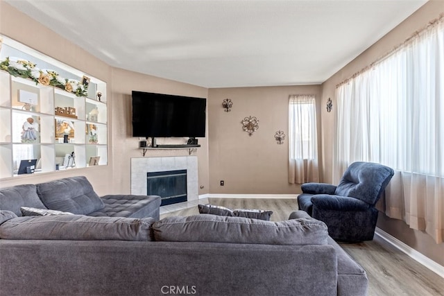 living room with a tiled fireplace and light wood-type flooring