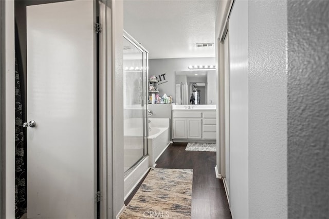 bathroom with wood-type flooring, shower with separate bathtub, vanity, and a textured ceiling