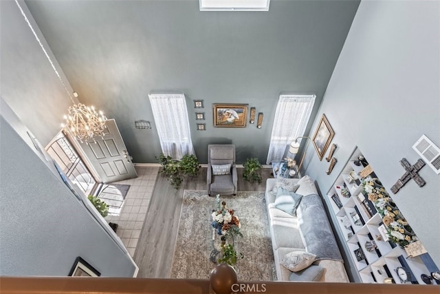 living room with an inviting chandelier, hardwood / wood-style flooring, and a high ceiling