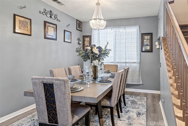 dining space with hardwood / wood-style flooring and a chandelier