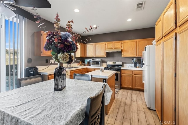 kitchen featuring sink, a center island, gas stove, light wood-type flooring, and white fridge