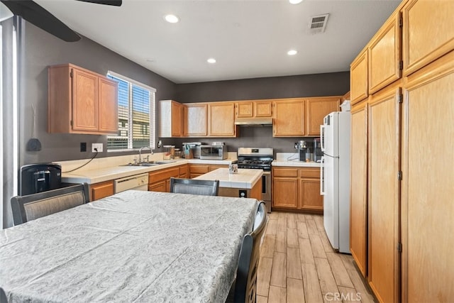 kitchen with sink, white refrigerator, a center island, light hardwood / wood-style floors, and stainless steel gas range