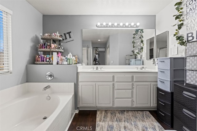 bathroom with vanity, wood-type flooring, and a tub