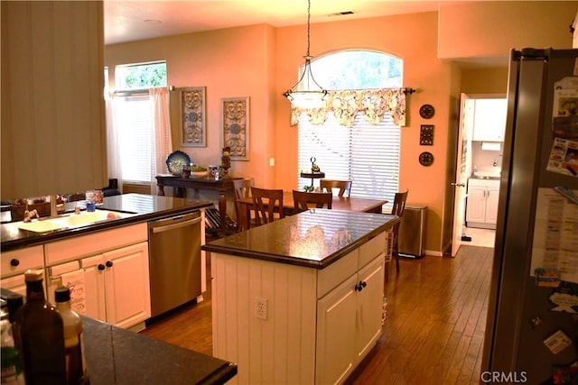 kitchen with pendant lighting, sink, appliances with stainless steel finishes, white cabinets, and a kitchen island