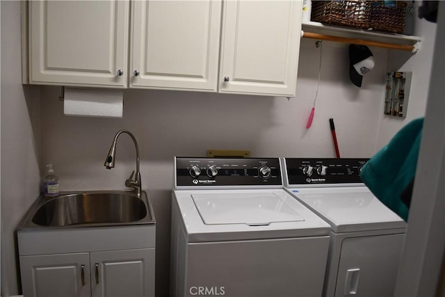 clothes washing area with cabinets, washer and clothes dryer, and sink