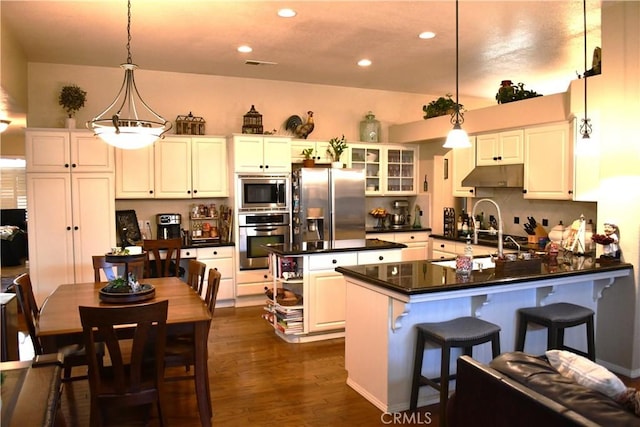 kitchen with stainless steel appliances, pendant lighting, white cabinets, and a kitchen bar