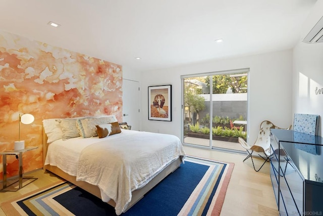 bedroom with access to exterior, light hardwood / wood-style floors, and an AC wall unit