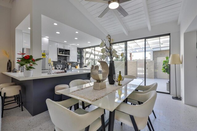 dining area featuring lofted ceiling with beams, wooden ceiling, and ceiling fan