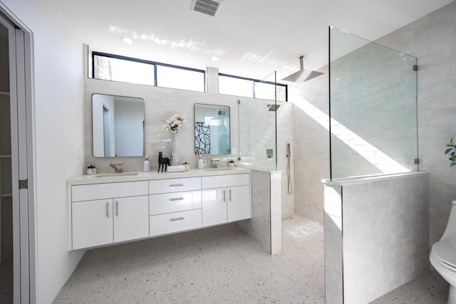 bathroom with tiled shower, vanity, and toilet