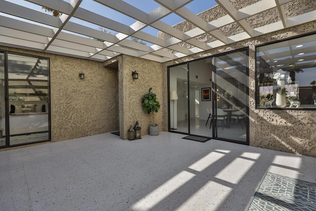 view of exterior entry with a pergola and a patio