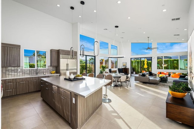 kitchen featuring sink, backsplash, stainless steel built in refrigerator, a kitchen island, and decorative light fixtures