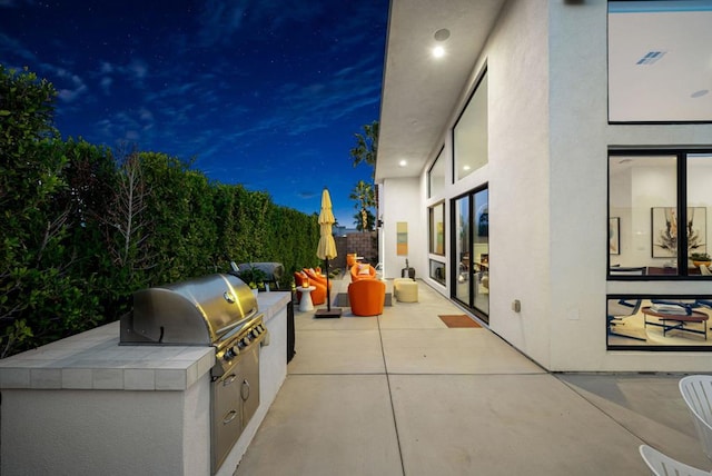 patio at night with an outdoor kitchen and a grill