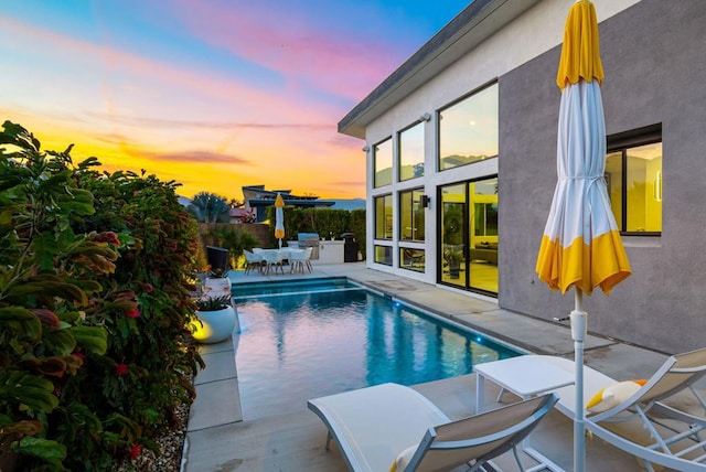 pool at dusk featuring a patio area