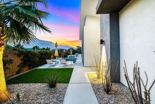 yard at dusk featuring a fenced in pool, a patio area, and a mountain view