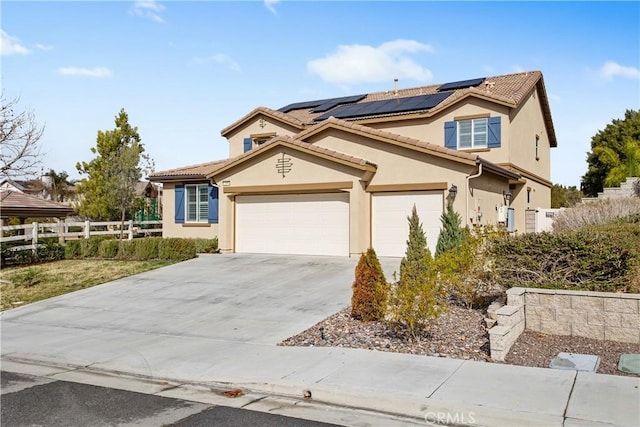 view of front of home with solar panels, fence, concrete driveway, a tiled roof, and stucco siding