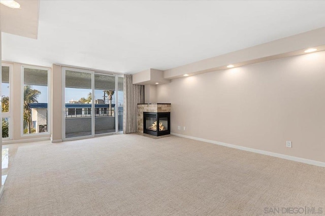 unfurnished living room featuring light carpet, a fireplace, and expansive windows