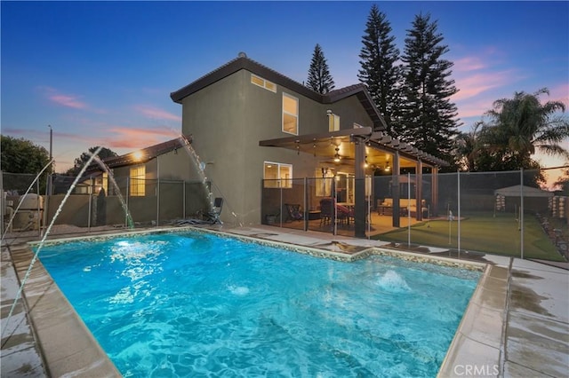 pool at dusk featuring a patio and pool water feature