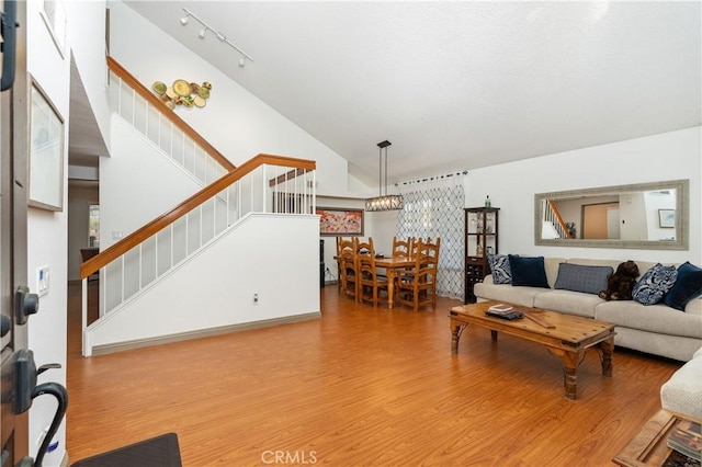 living room featuring hardwood / wood-style flooring, track lighting, and high vaulted ceiling