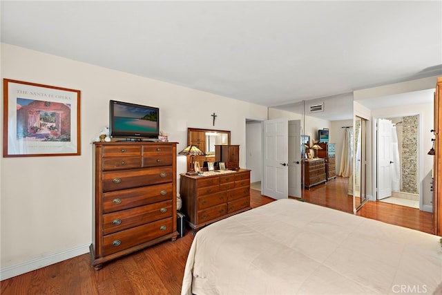 bedroom with ensuite bath and wood-type flooring