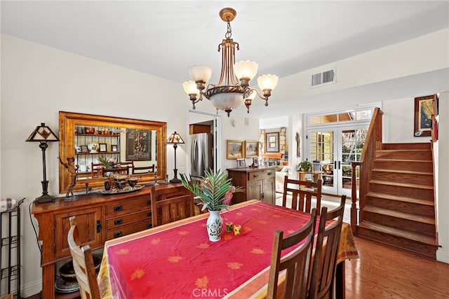 dining room featuring french doors, hardwood / wood-style floors, and a notable chandelier